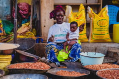 2 June 2015: women selling grains at the market while taking care of children, Kankan, Upper-Guinea, Republic of Guinea, West Africa