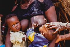 sein avecl'aide de sa vieille parente, village traditionnel Baga environ de Boffa Basse-Guinée, Républiqe de Guinée,                            6 July 2014, mother breastfeeding her son with the support of her elderly relative, Baga traditional village, Boffa vicinity, Lower-Guinea, Republic of Guinea